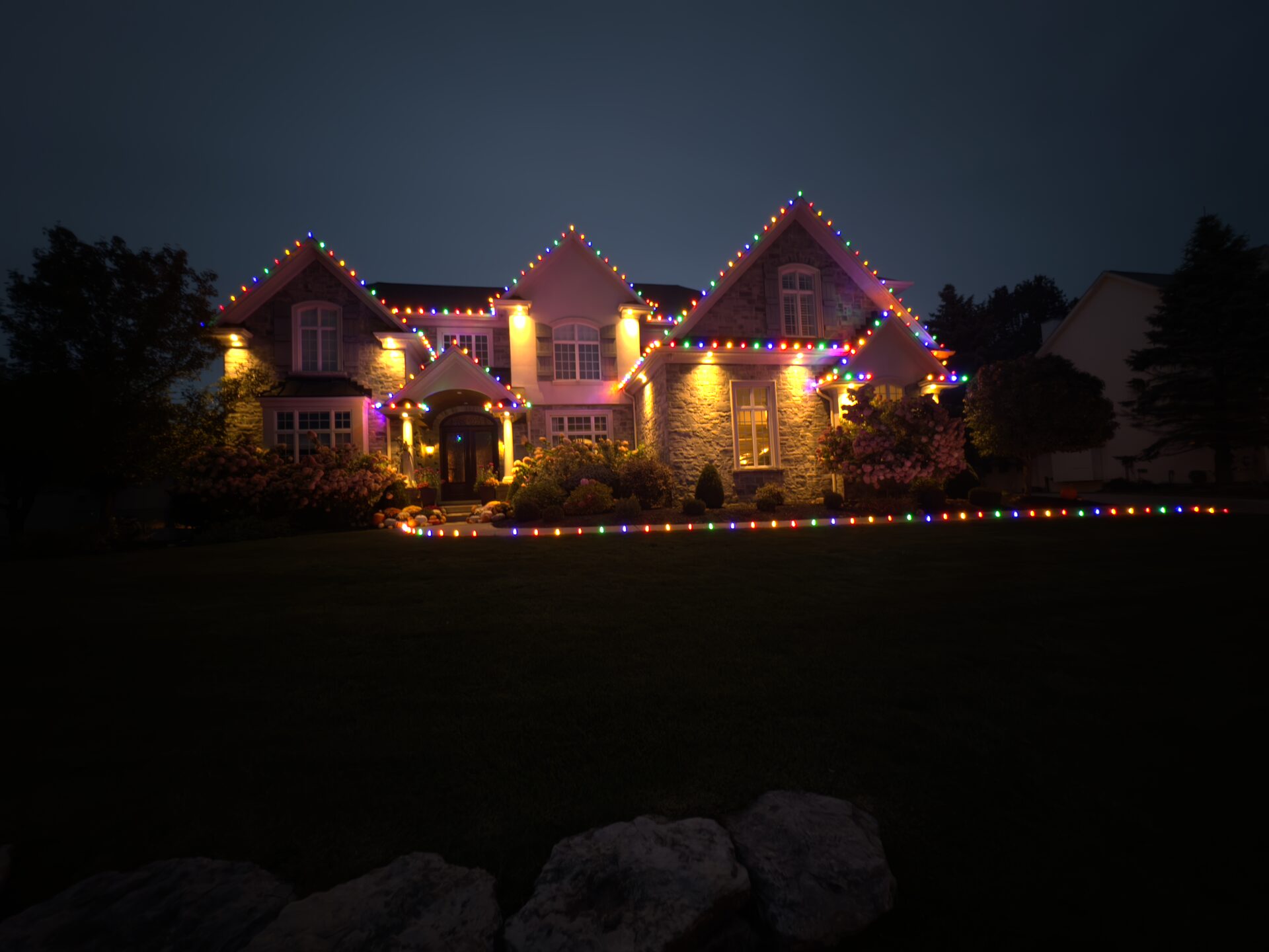 Rochester area home with multicolor roofline Christmas lights and a lit walkway border